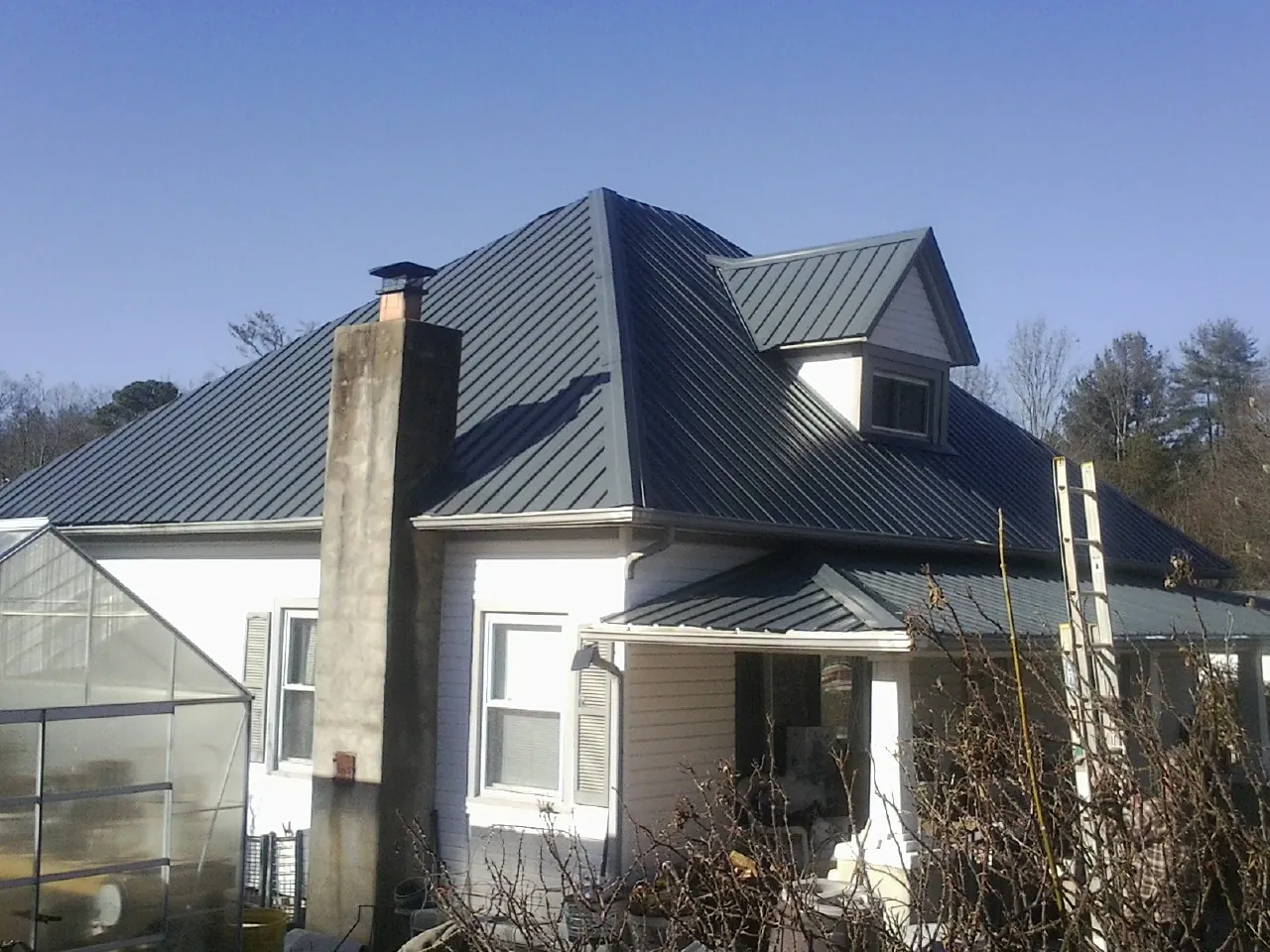 Dark blue standing seam metal roof on a white farmhouse with dormer — Slate & Tile Roof Repair by Roofing Brothers in Low Moor