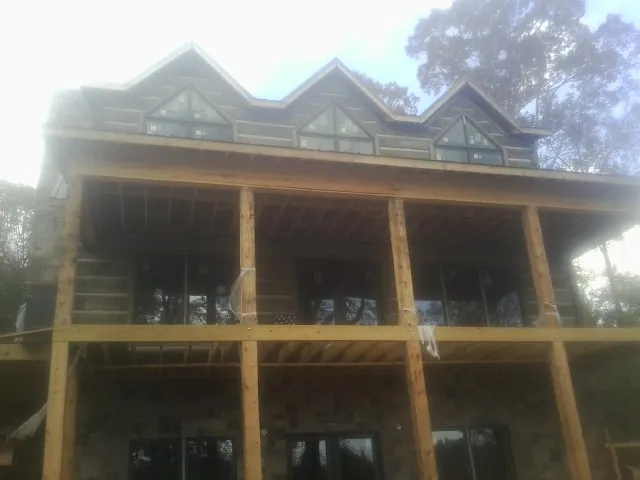 Dormers and porch framing on a large log home under construction — Roof Coating work by our crew in Low Moor