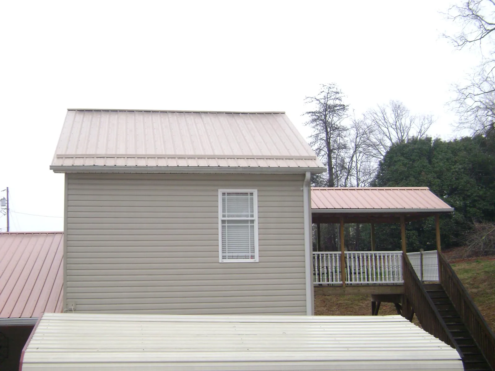 Tan metal roofs on a two story addition and attached porch, from a Roof Replacement job in Low Moor